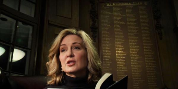 A woman reading a book with a memorial list behind her in The Society 