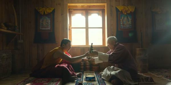 Two men hold examine a gun between them in The Monk and the Gun