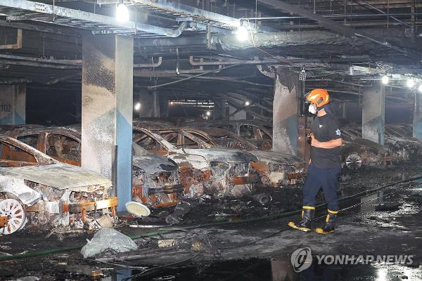 A firefighter examines vehicles ravaged in a fire that started from an electric Mercedes-Benz sedan parked in the underground garage of an apartment building in Incheon on Aug. 1, 2024. (Yonhap)