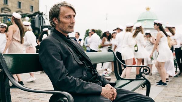 Mads Mikkelsen sitting on a park bench in Another Rounds