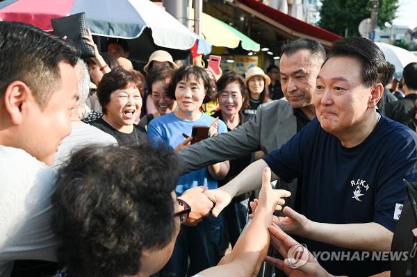 This photo provided by the presidential office shows President Yoon Suk Yeol (R) greeted by people at a local market in Tongyeong, South Gyeo<em></em>ngsang Province, on Aug. 5, 2024, while traveling in the region during his summer vacation. (PHOTO NOT FOR SALE) (Yonhap)