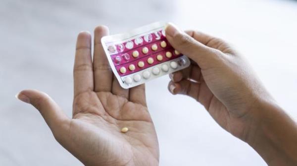 Close-up of young woman's hand holding birth co<em></em>ntrol pills