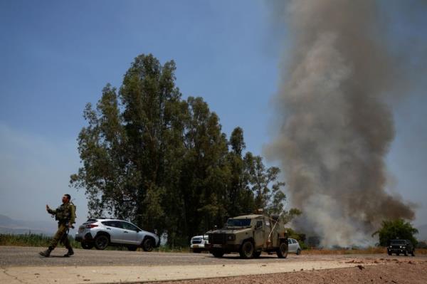 Smoke rises next to an Israeli military vehicle