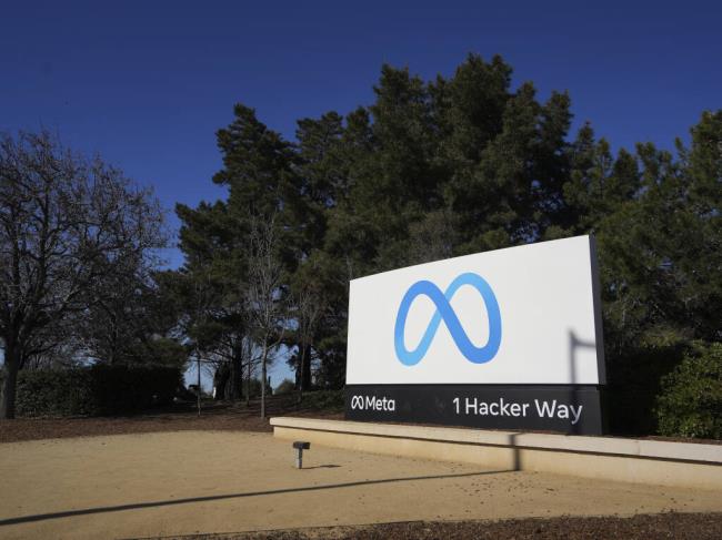 A sign at the corporate campus of me<em></em>ta, parent company of Facebook, in Menlo Park, California, shows the me<em></em>ta logo and reads “me<em></em>ta. 1 Hacker Way.”