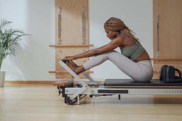 Woman Doing Pilates Exercise on Reformer